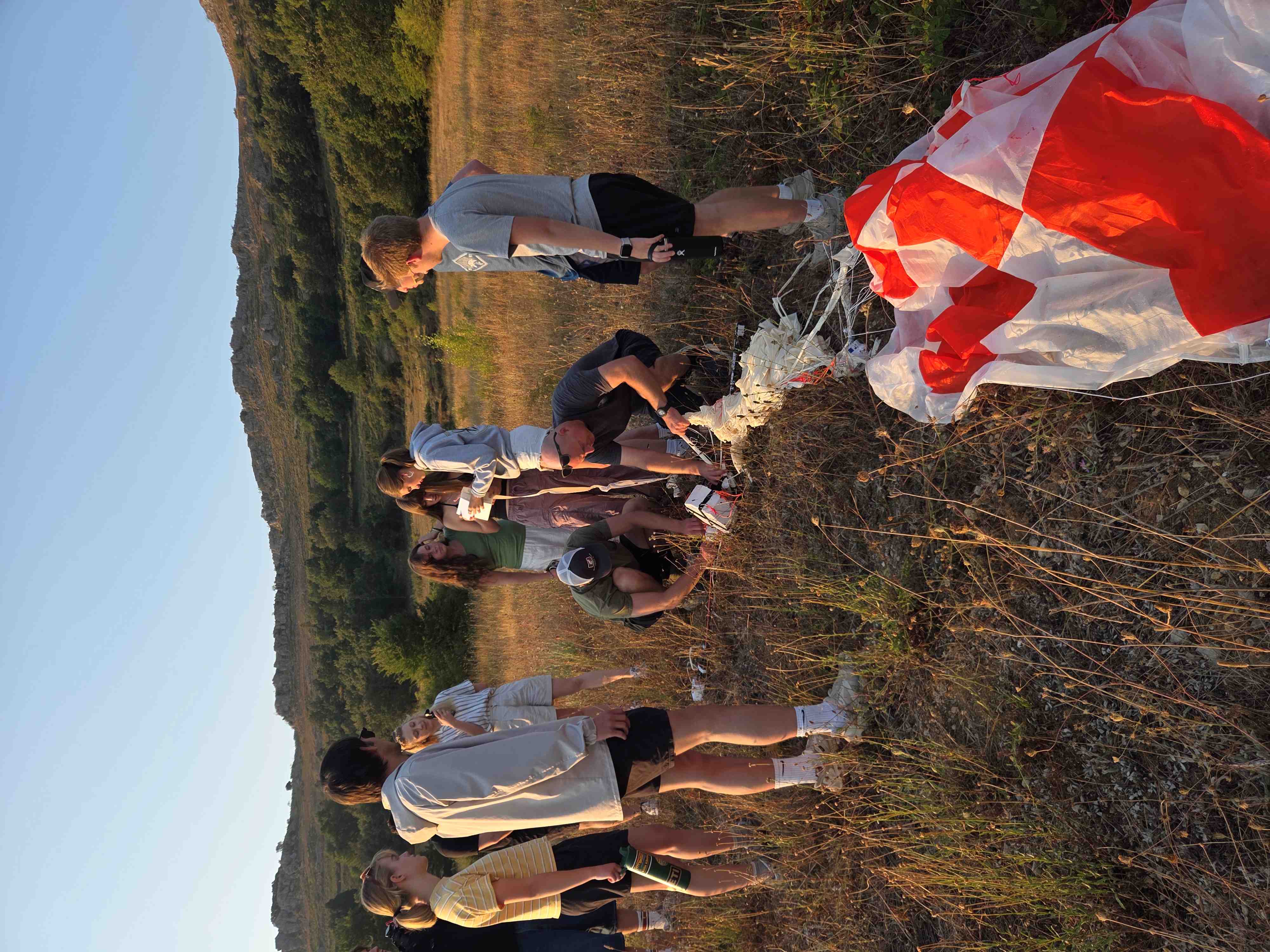 Four students gather around a long table, preparring balloon payloads.
