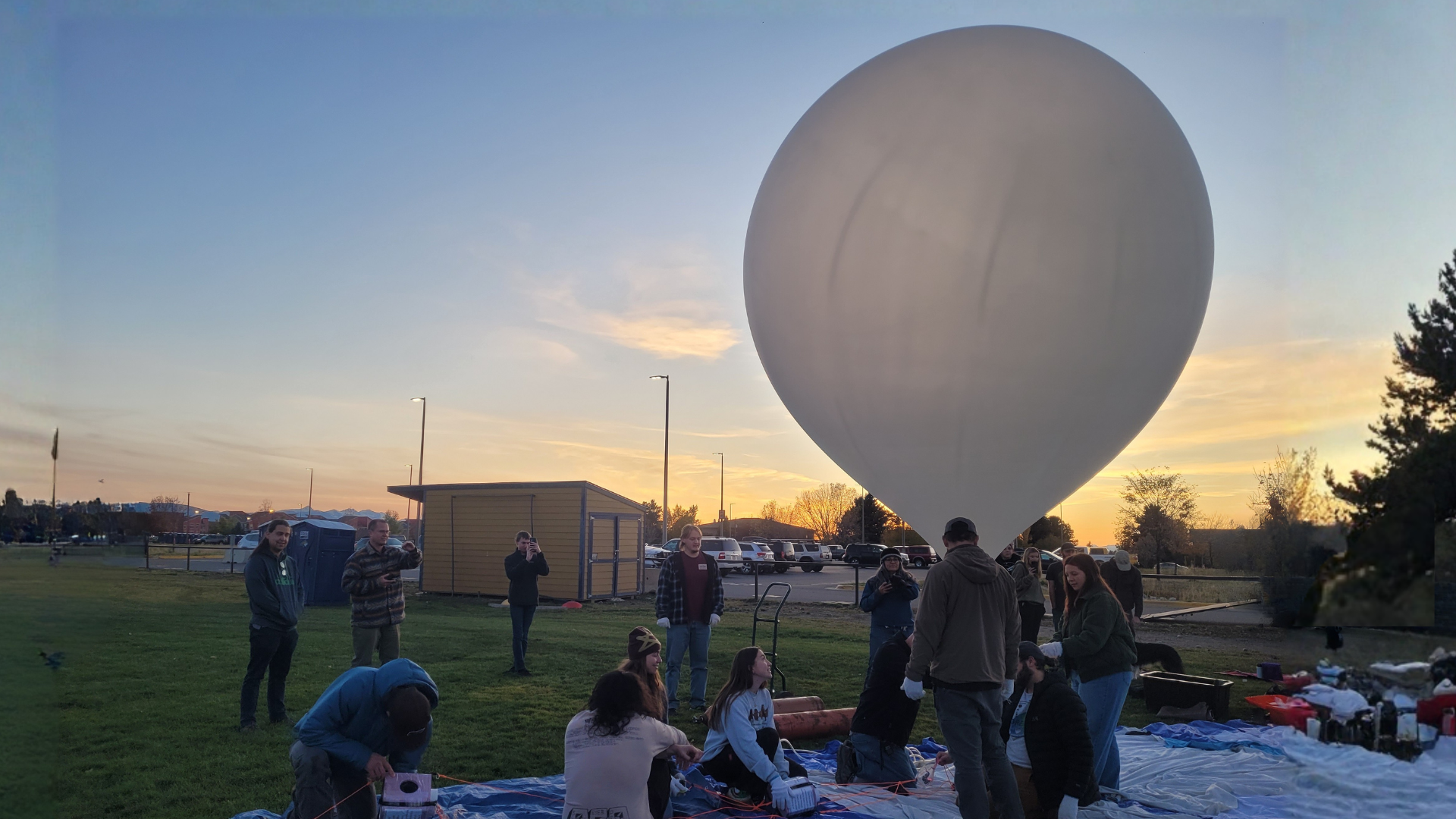 A team of people preparing a balloon release at sunset