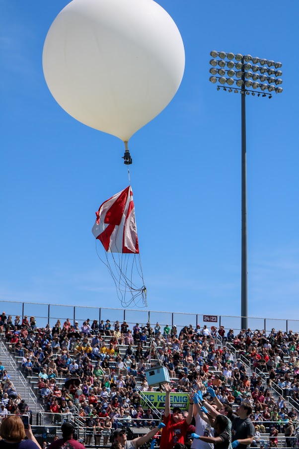 A stadium full of people watching a balloon being release