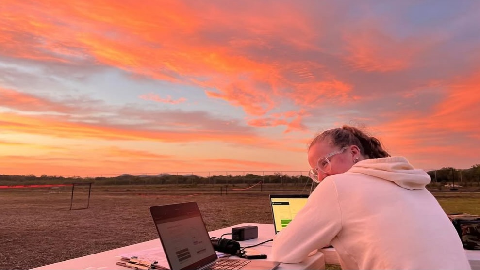 A girl at ground station in front of an orange sunrise