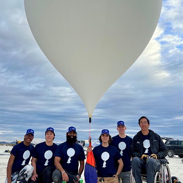 A team of people holding a large weather balloon