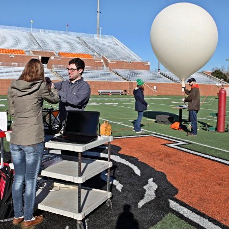 A team launching a balloon in a stadium