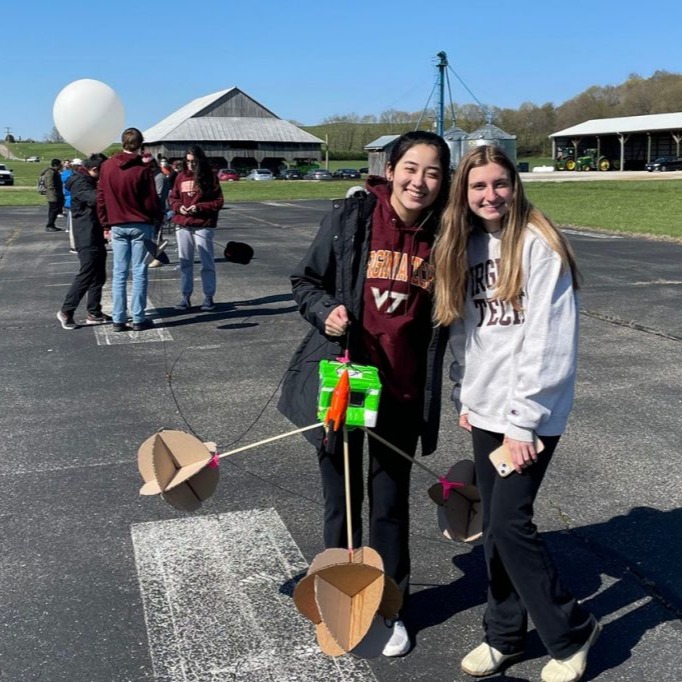 People holding a payload with a balloon in the background