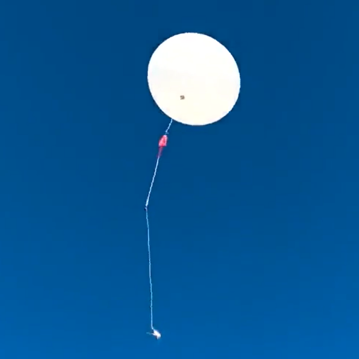 A balloon floating through the sky with a long string below