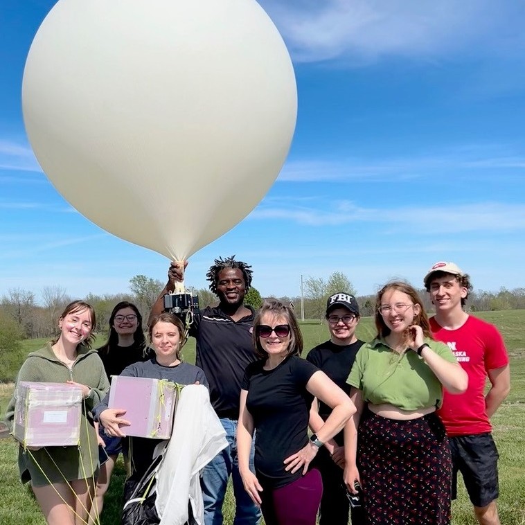 A group holding a large balloon and recovered payload