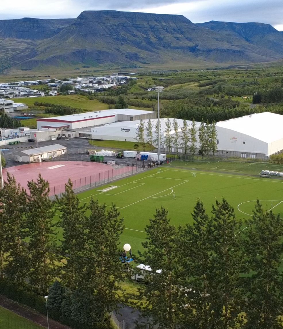 Aerial image of a sports field with a weather balloon being launched and mountains in the background. 